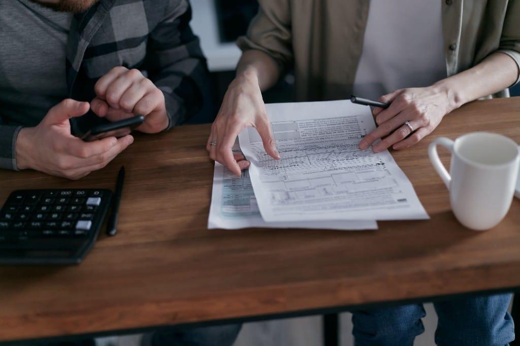 Counsel and a financial analyst reviewing documents, calculations, and a calculator while evaluating a financial expert for litigation